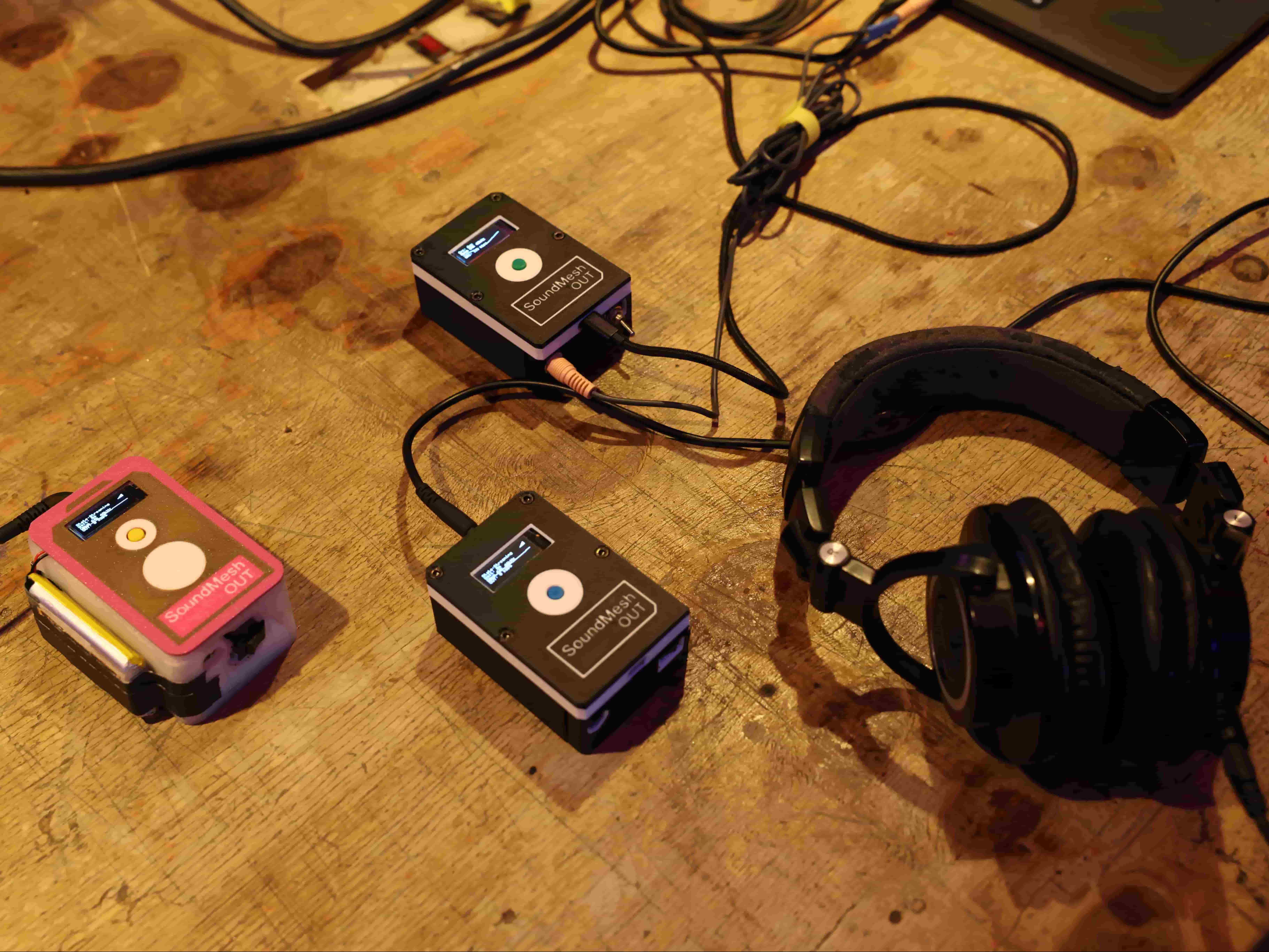 SoundMesh prototype: hands operating wireless audio hardware on a workbench.